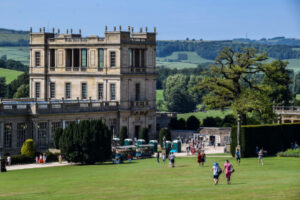 A breathtaking view of Chatsworth House, a stately home surrounded by lush greenery and rolling hills.