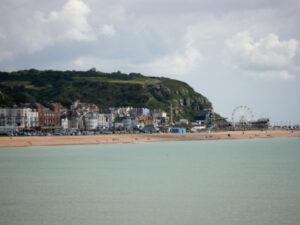 A picturesque view of Hastings Beach, with soft golden sand, clear blue waters, and a charming coastal town in the background.
