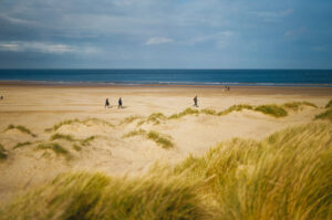 A picturesque view of Holkham Beach in Norfolk, showcasing its expansive golden sands and azure blue waters.